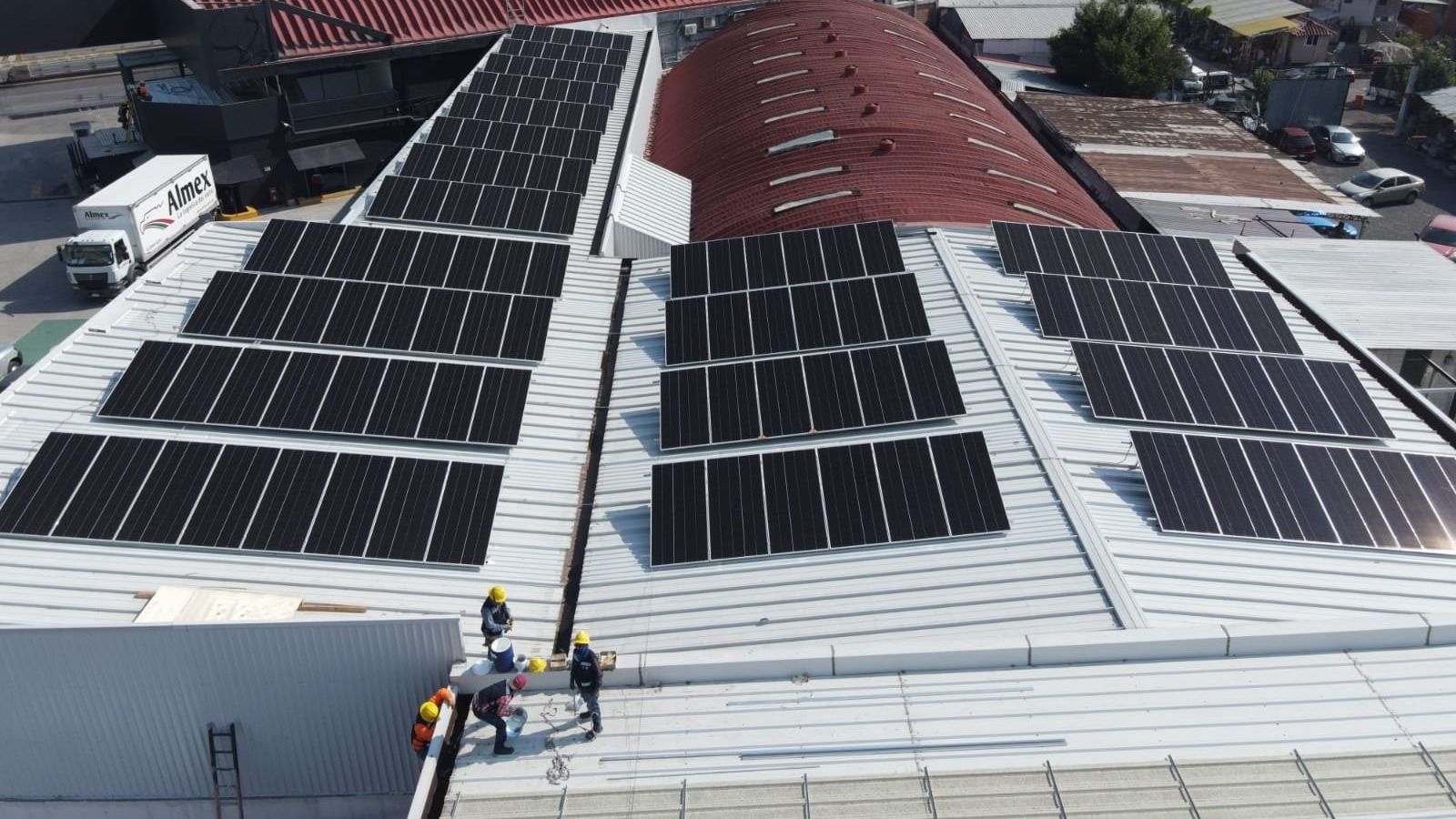 Techo de una agencia automotriz con filas de paneles solares, visto desde dron
