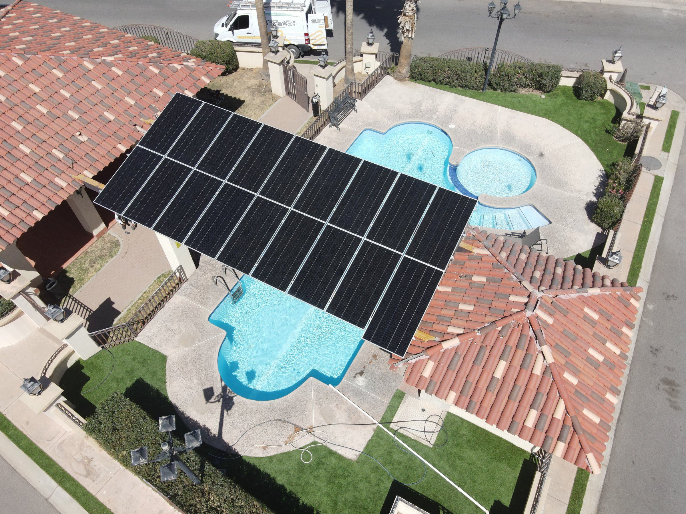 Pérgola con paneles solares junto a una alberca en un área común de Hermosillo, vista desde dron