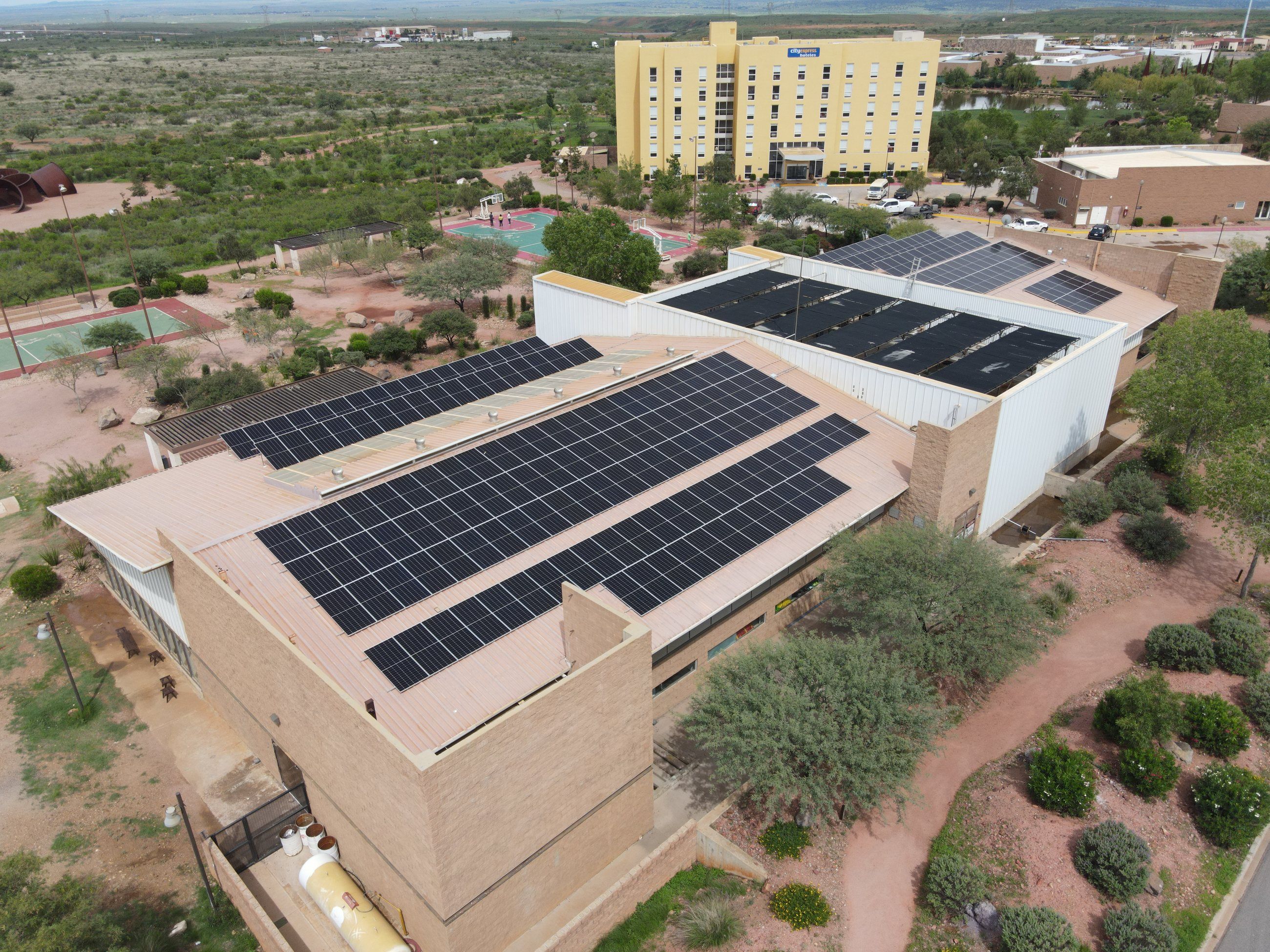 Edificio de Grupo México en Cananea con paneles solares en el techo, entre árboles y cerros, visto desde dron
