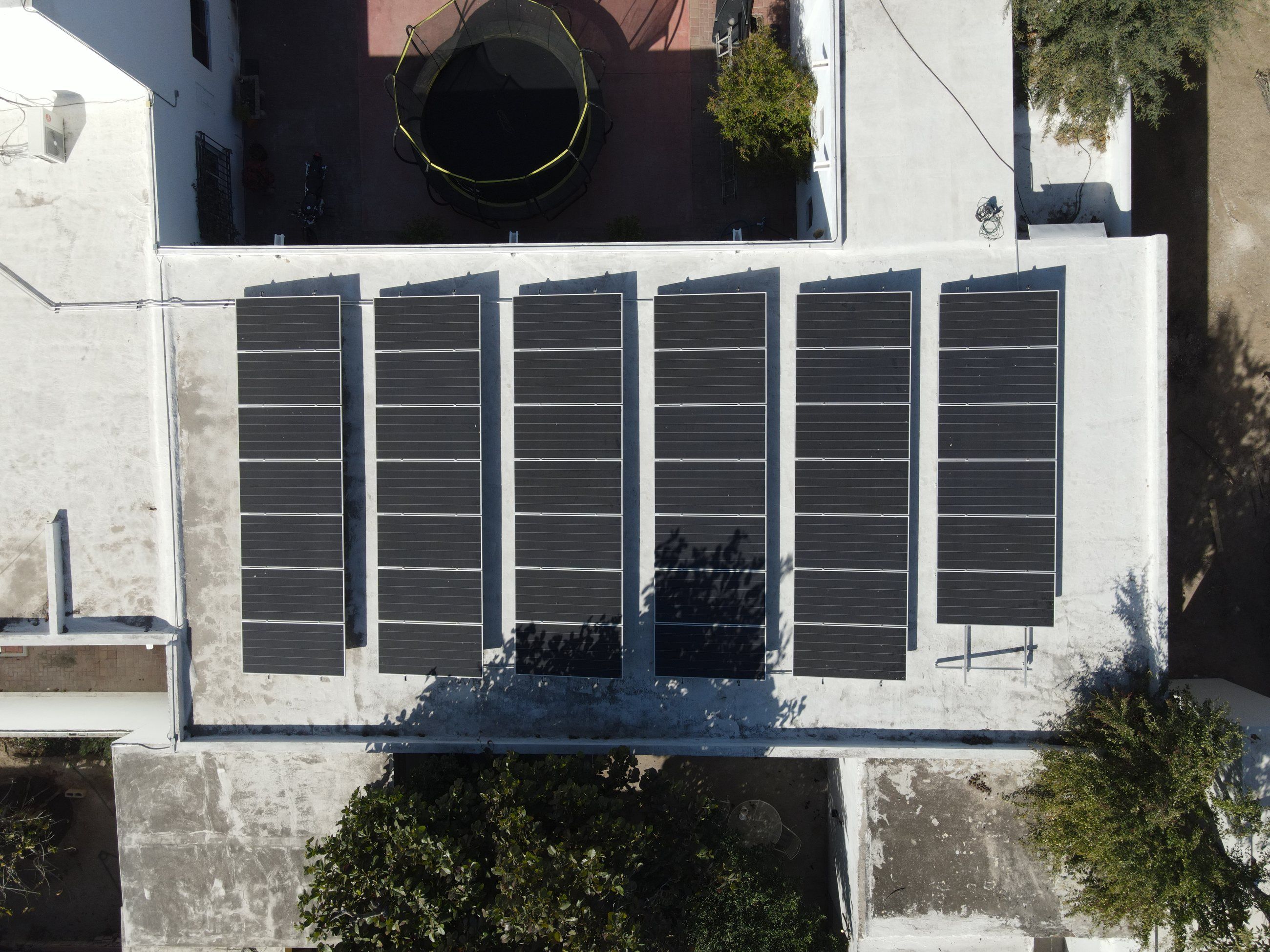 Seis filas de paneles solares sobre una azotea plana, vistas desde arriba con dron