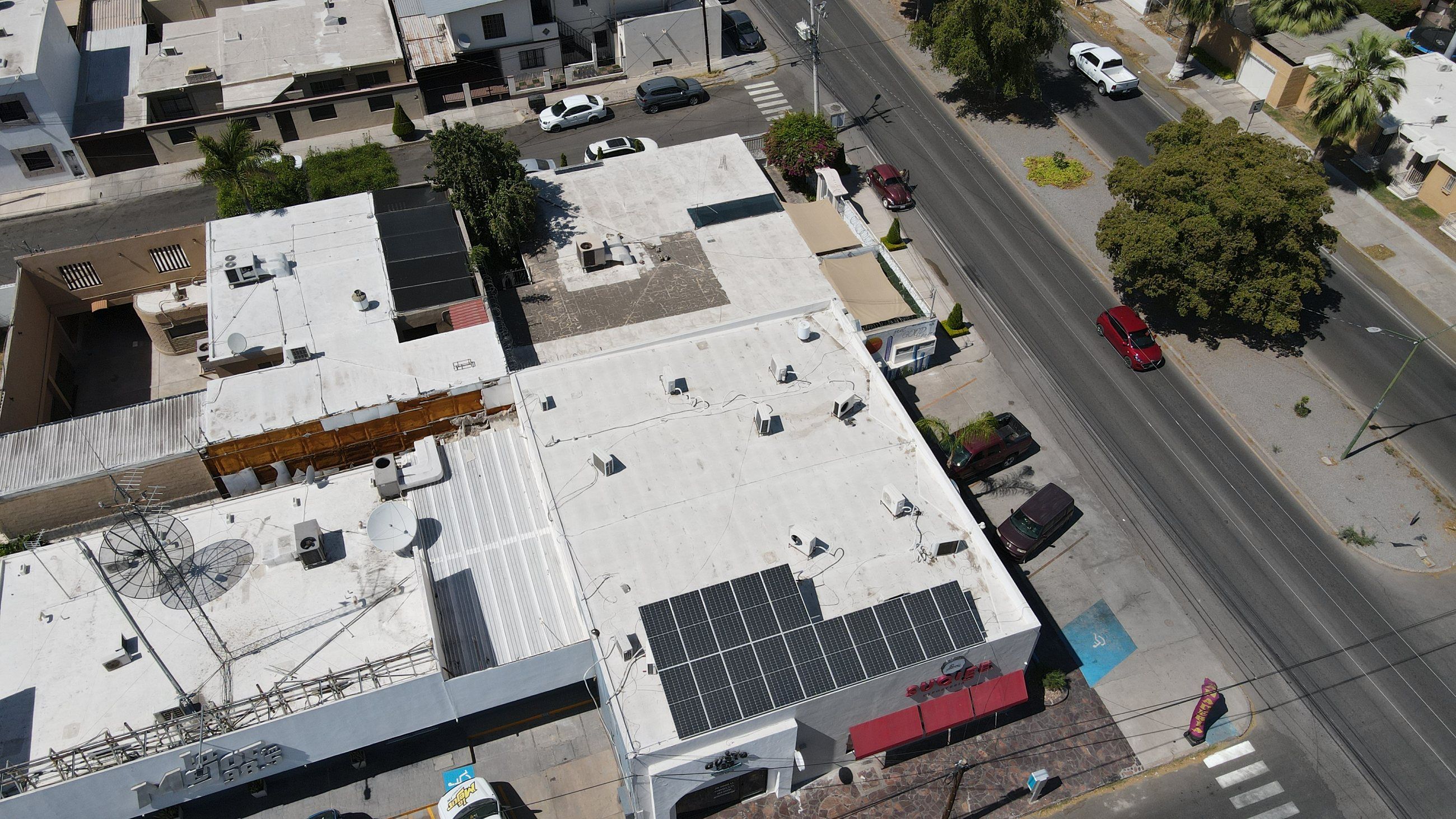 Locales comerciales en una avenida de Hermosillo con paneles solares en la azotea, vistos desde dron