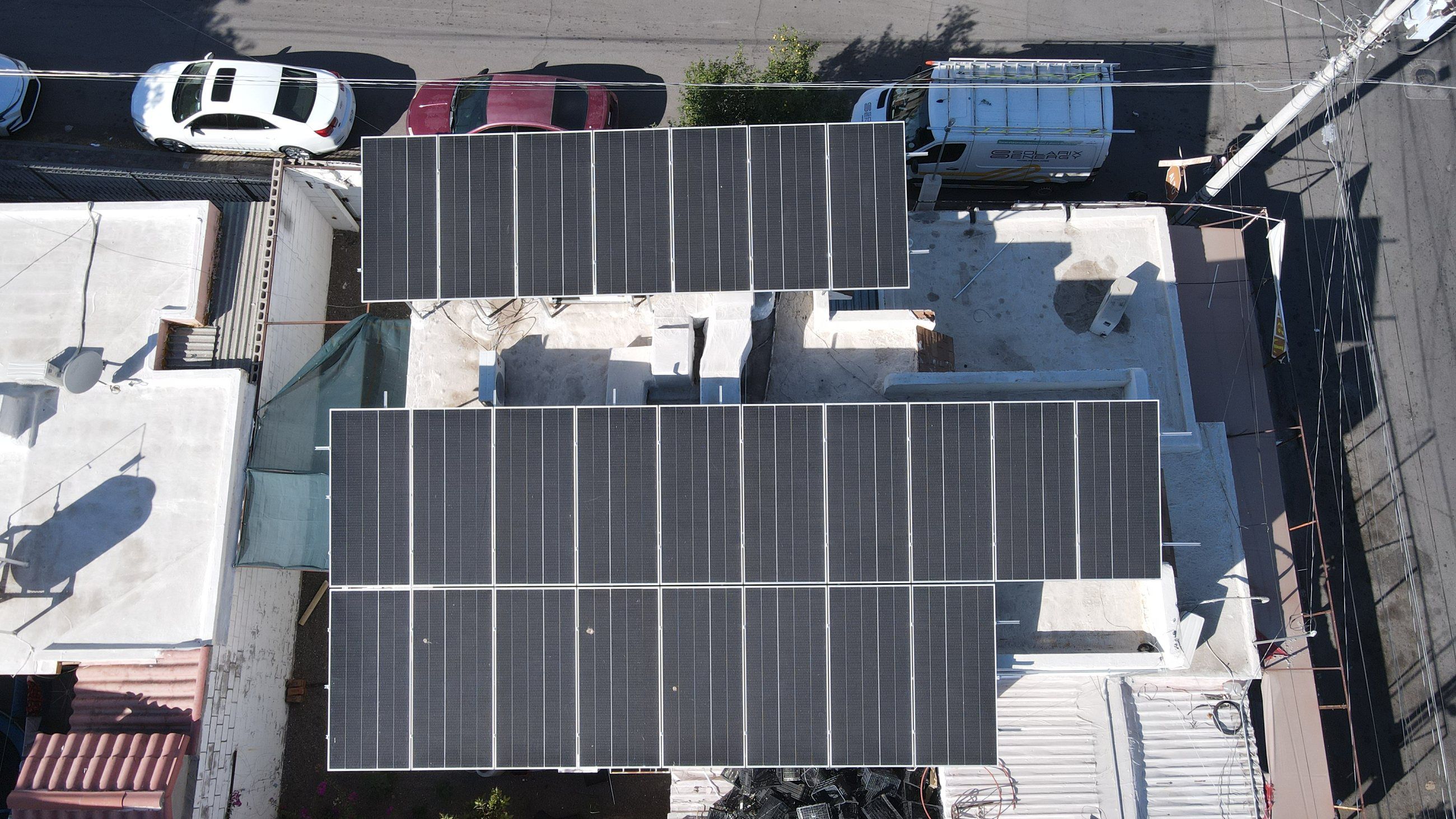 Dos arreglos grandes de paneles solares sobre las azoteas de un comercio en Hermosillo, vistos desde arriba con dron