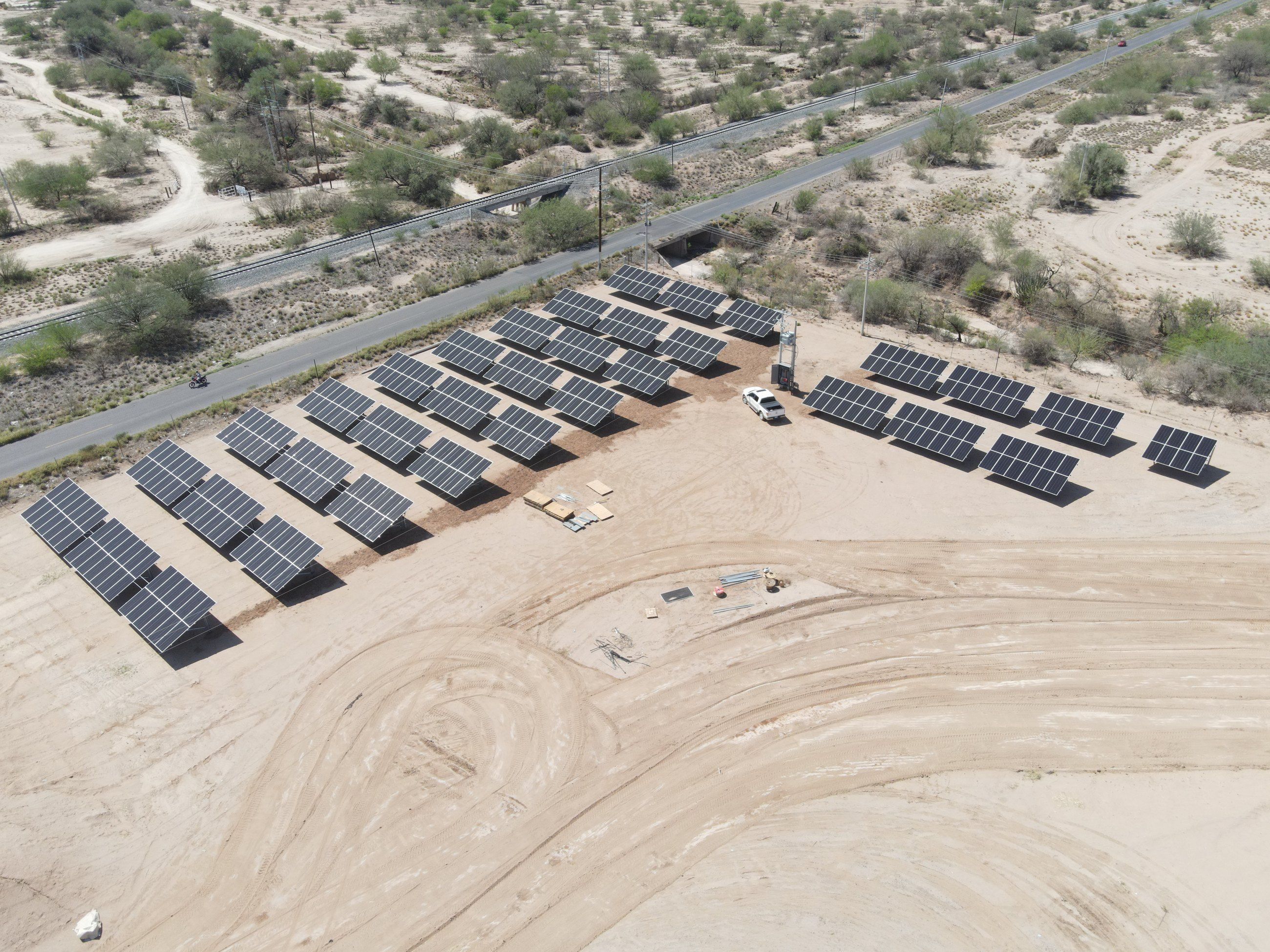 Sistema solar de Gresba sobre suelo: filas de mesas de paneles en un terreno desértico junto a una carretera, vista desde dron