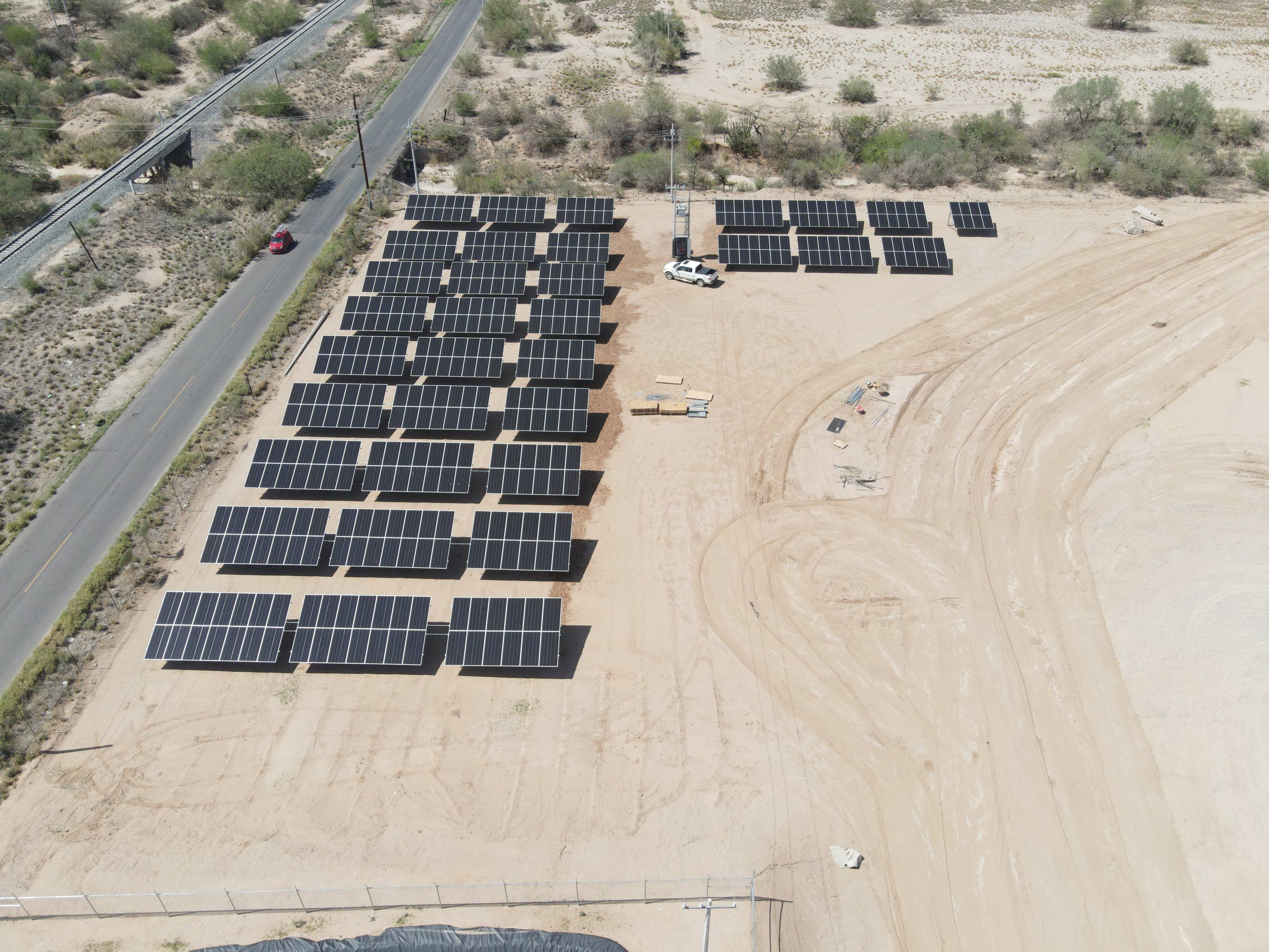 Sistema solar sobre suelo: mesas de paneles en un terreno de tierra, vistas desde dron