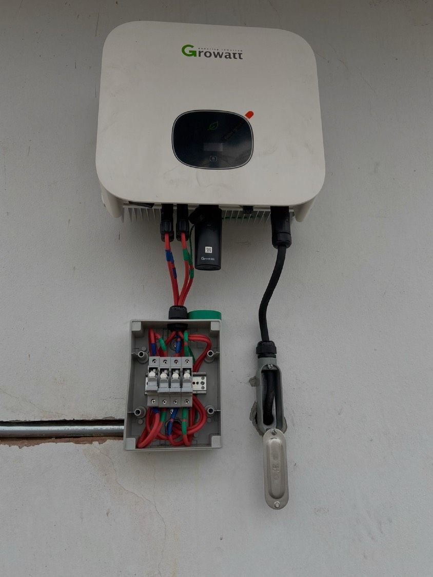 Inversor Growatt montado en muro con su desconectador y el cableado