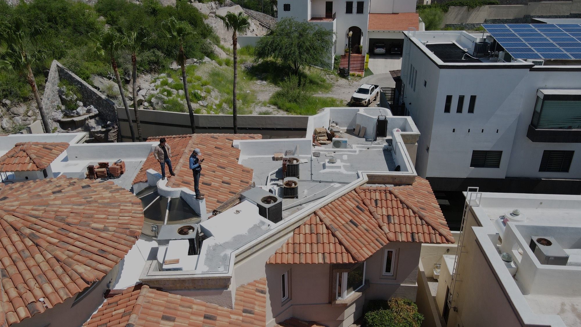 Dos técnicos de Solarix midiendo una azotea de teja durante una visita técnica, vistos desde el dron